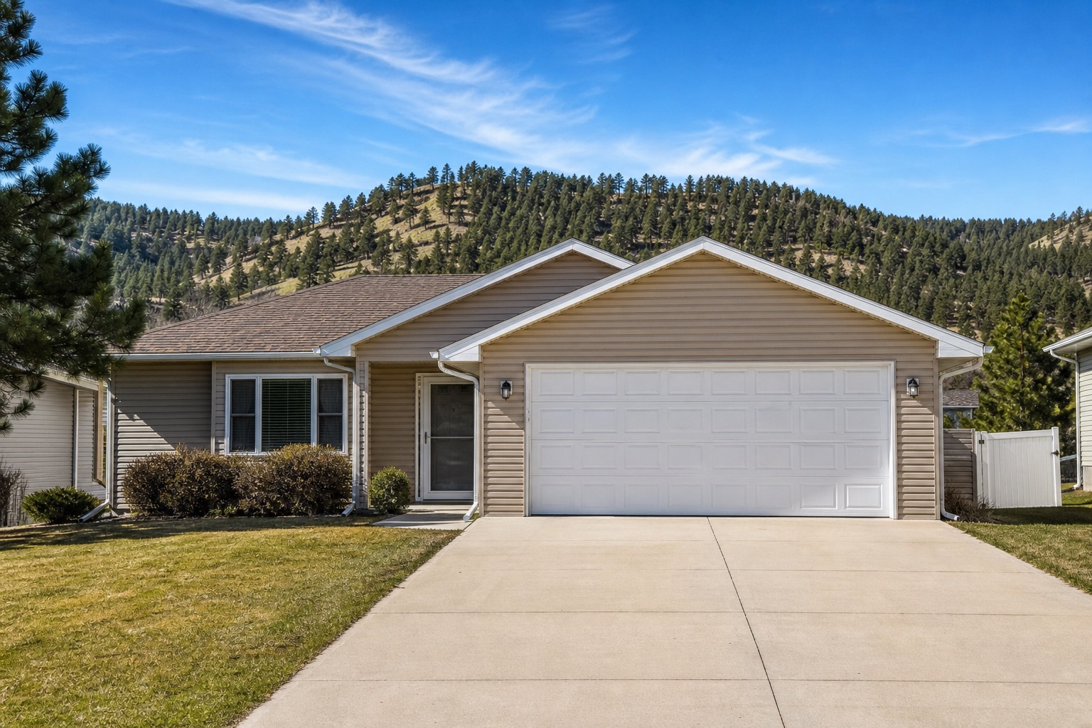 Ranch home with garage doors and Black Hills pines near Rapid City